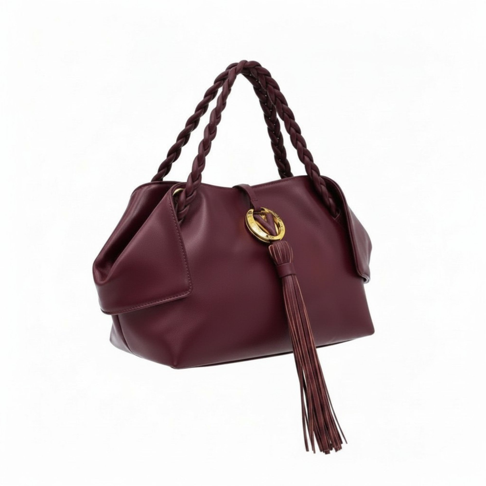 Left three-quarter studio view of a premium burgundy leather handbag featuring unique folded side wings, braided top handles, and a signature gold-tone logo emblem with a long leather tassel, available at BLUE SALON.