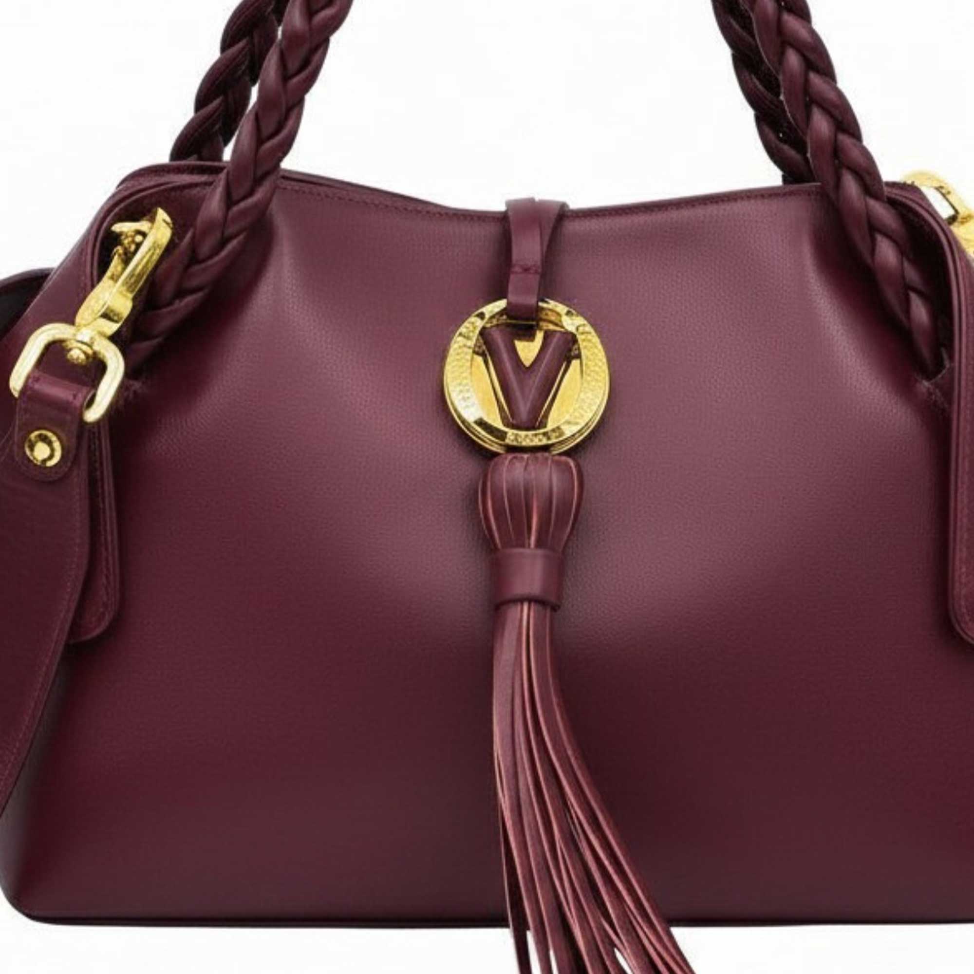 Macro close-up shot of the handbag highlighting the intricate gold-tone circular "V" logo hardware, smooth burgundy leather stitching, and the top construction of the long leather tassel, available at BLUE SALON.