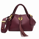 Burgundy leather handbag with braided top handles, a matching shoulder strap, a gold-tone "V" logo emblem, and a long hanging tassel detail at the front, available at BLUE SALON.