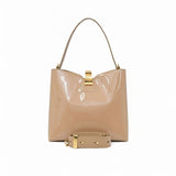 Rear view of the glossy beige patent leather bag with its detachable shoulder strap coiled neatly in the foreground.