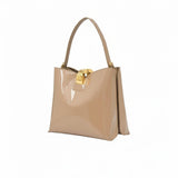 Three-quarter perspective view of the glossy beige patent leather handbag, showcasing its gold-accented hardware.