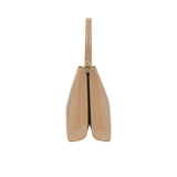 Side profile view of the sleek beige patent leather handbag showing its structured dual-compartment gusset design.