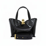 Black patent leather handbag with gold accents on a white background.