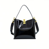 Front view of the Black patent leather bag styled with its wide, detachable matching shoulder strap attached.