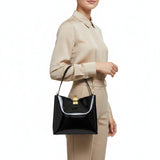 Person holding a black handbag with a white interior on a white background.