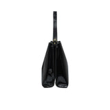 Side profile view of the sleek Black patent leather handbag showing its structured dual-compartment gusset design.