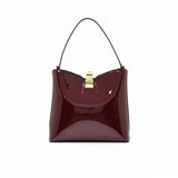Front view of a burgundy patent leather shoulder bag with a gold-tone clasp closure, available at Blue Salon.