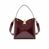 Front view of a burgundy patent leather shoulder bag with a gold-tone clasp closure, available at Blue Salon.