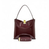Front view of the burgundy patent leather bag styled with its wide, detachable matching shoulder strap attached.