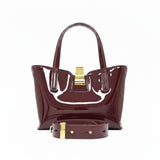 Rear view of the burgundy patent leather handbag, displayed with its detachable matching leather shoulder strap neatly rolled and resting in front.