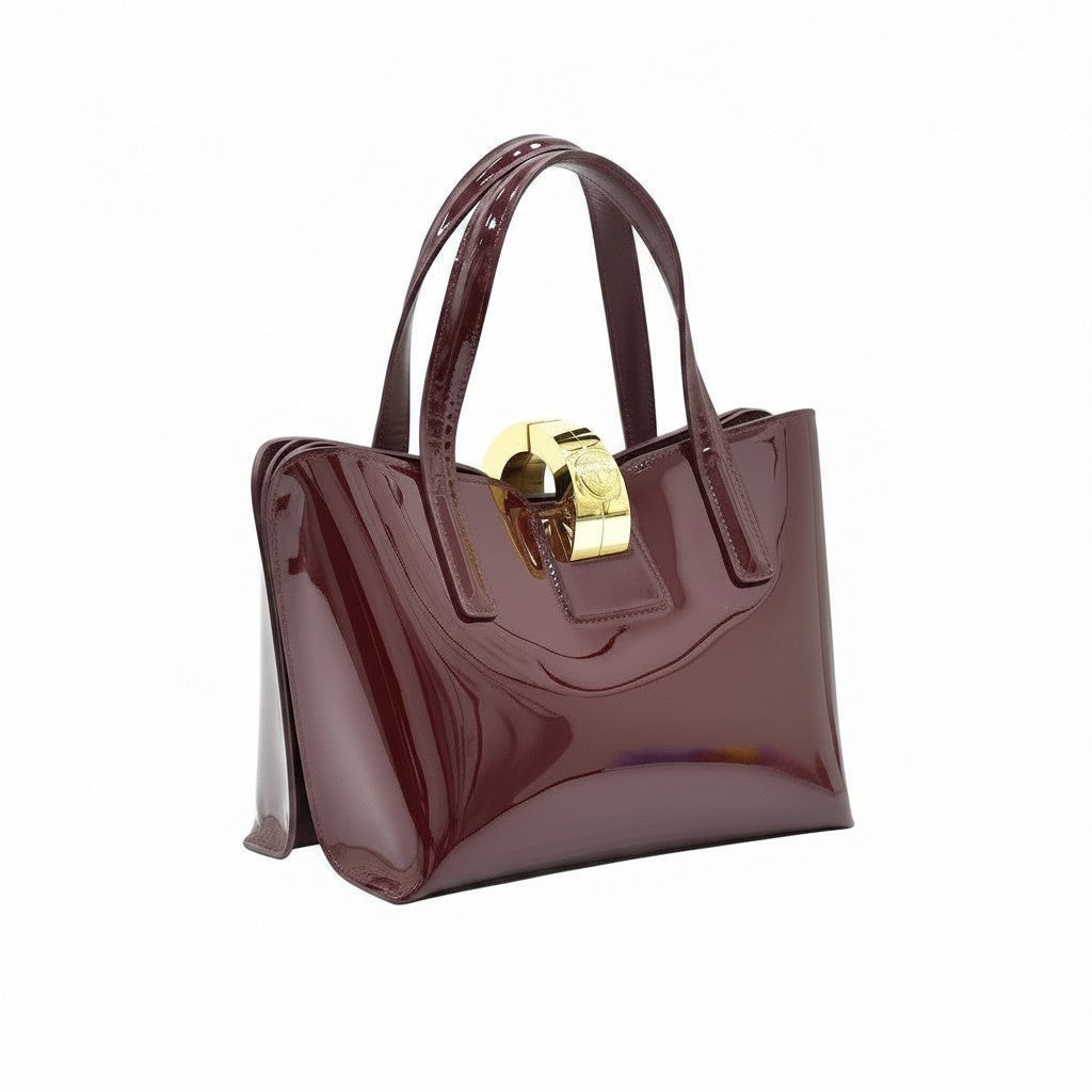 Three-quarter left angle view of the premium burgundy leather bag, highlighting the clean lines and polished gold-tone central closure.
