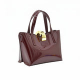 Three-quarter left angle view of the premium burgundy leather bag, highlighting the clean lines and polished gold-tone central closure.