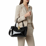 Woman in a beige suit holding a black handbag on a white background.