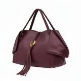 Three-quarter left angle view of the burgundy leather tote bag showcasing its supple grain leather texture and structured silhouette.