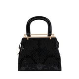 Front view of a black Valentino Orlandi patent leather handbag featuring an embossed floral damask pattern and gold-tone logo bar.
