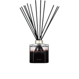 A 500ml Ormonde Jayne luxury reed diffuser featuring a square clear glass bottle filled with dark liquid, a silver collar, and a fanned-out arrangement of black reeds.