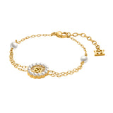 A three-quarter studio presentation of the Escada Clara bracelet showing the gold-plated dual cable chains linked to a central pearl-rimmed logo medallion, accent pearl stations, and an adjustable lobster clasp track.