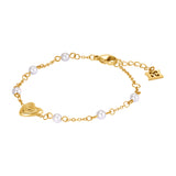 A full studio presentation layout of the Escada Mina bracelet, displaying the gold-plated cable chain, the central concentric ridge heart charm, the spaced round white pearl stations, and the adjustable lobster closure.