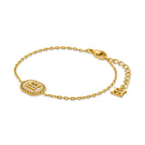 An overview studio product photograph of the Escada Grace bracelet, highlighting the gold-plated cable chain, the oval logo center motif with white crystal accents, and the lobster clasp with a dangling monogram end tag.