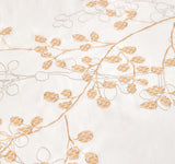 Detailed view of copper-gold botanical leaf embroidery on white fabric.
