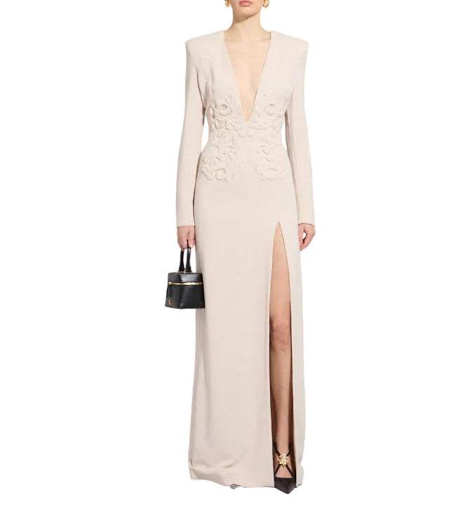 Whisper pink floor-length gown with deep V-neck, long sleeves, padded shoulders, high side slit, and floral appliqué on the b