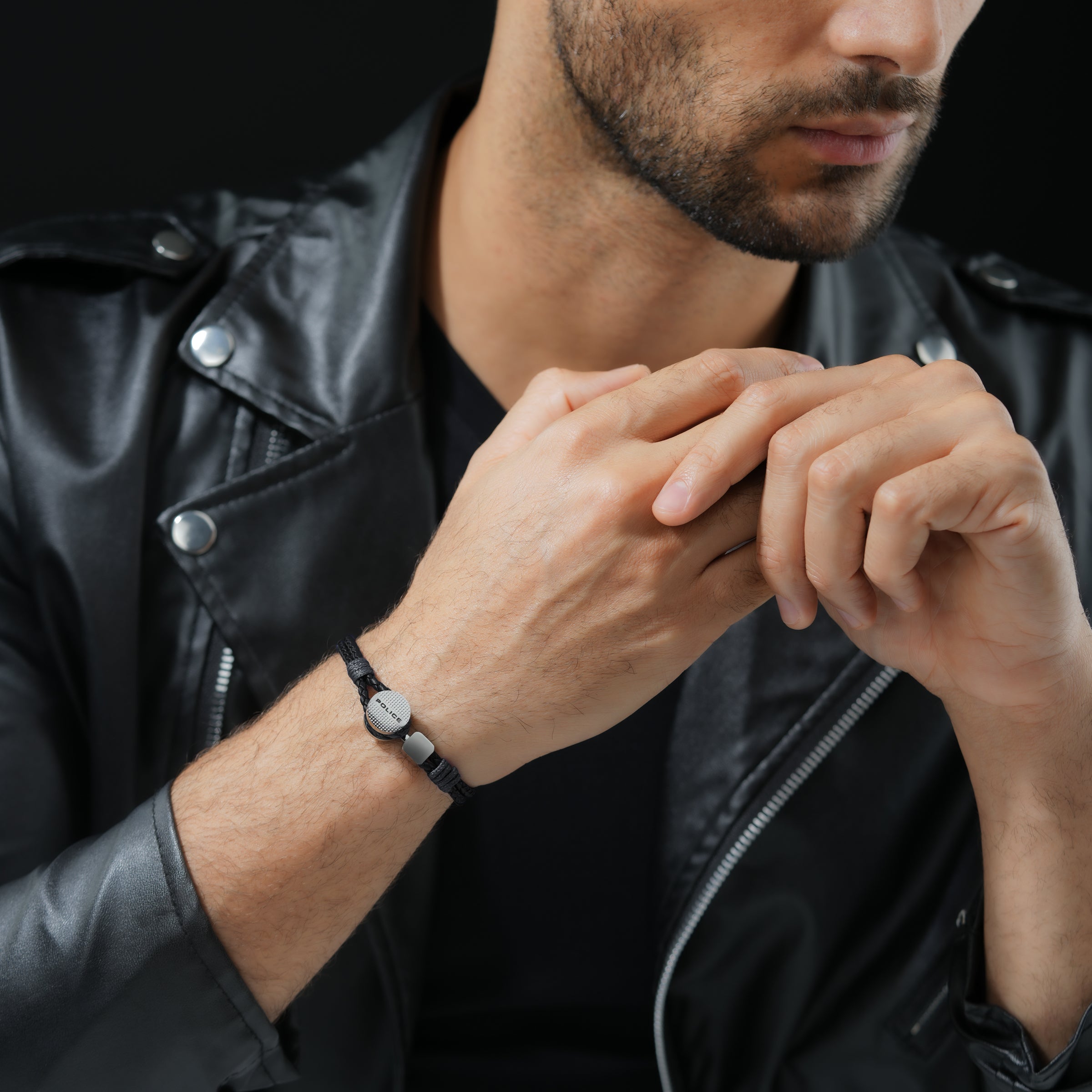 Black braided leather bracelet with a central round, textured silver-toned plate engraved "POLICE" and two rectangular silver