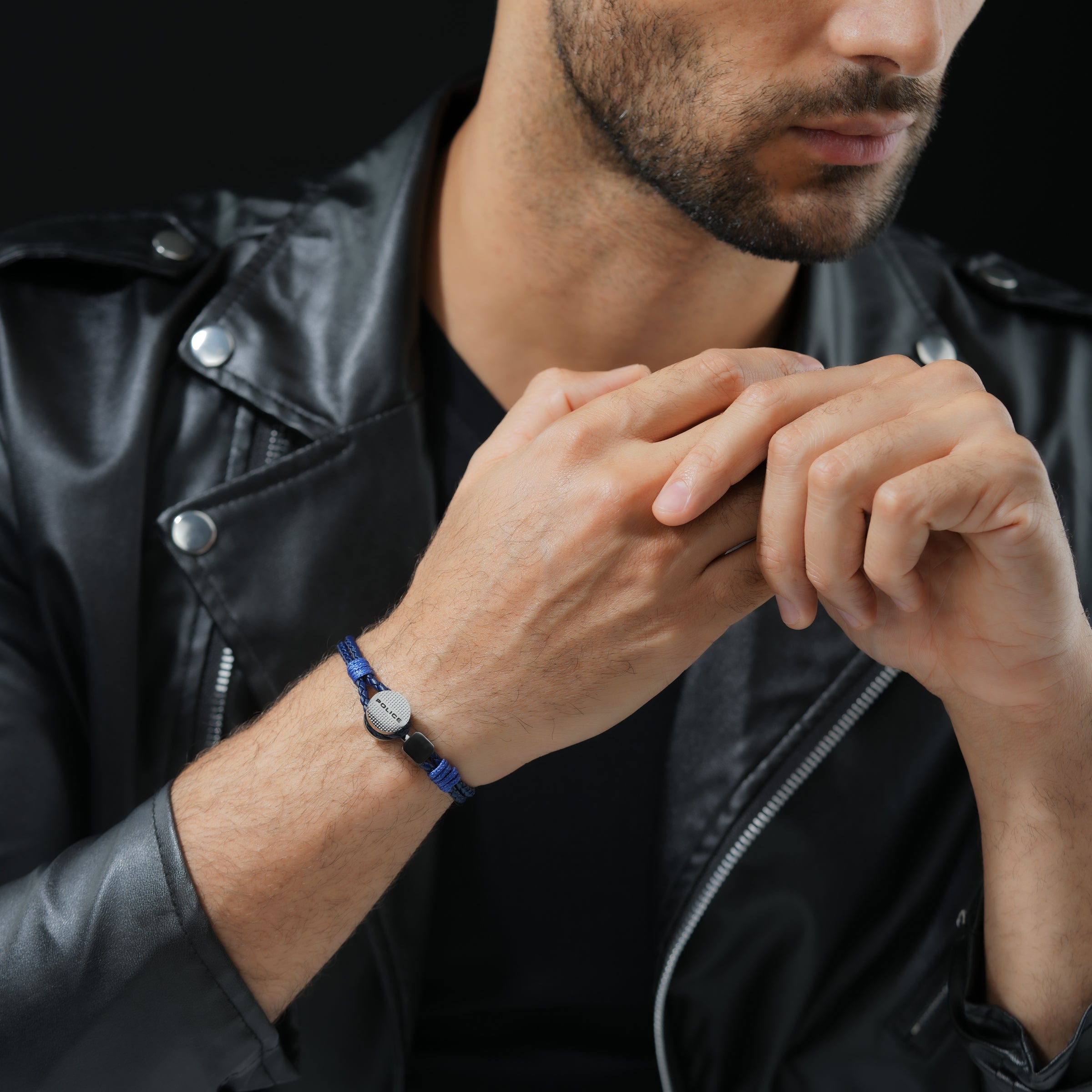 Navy blue braided leather bracelet with a silver-toned circular plate engraved 'POLICE' and dark rectangular beads.