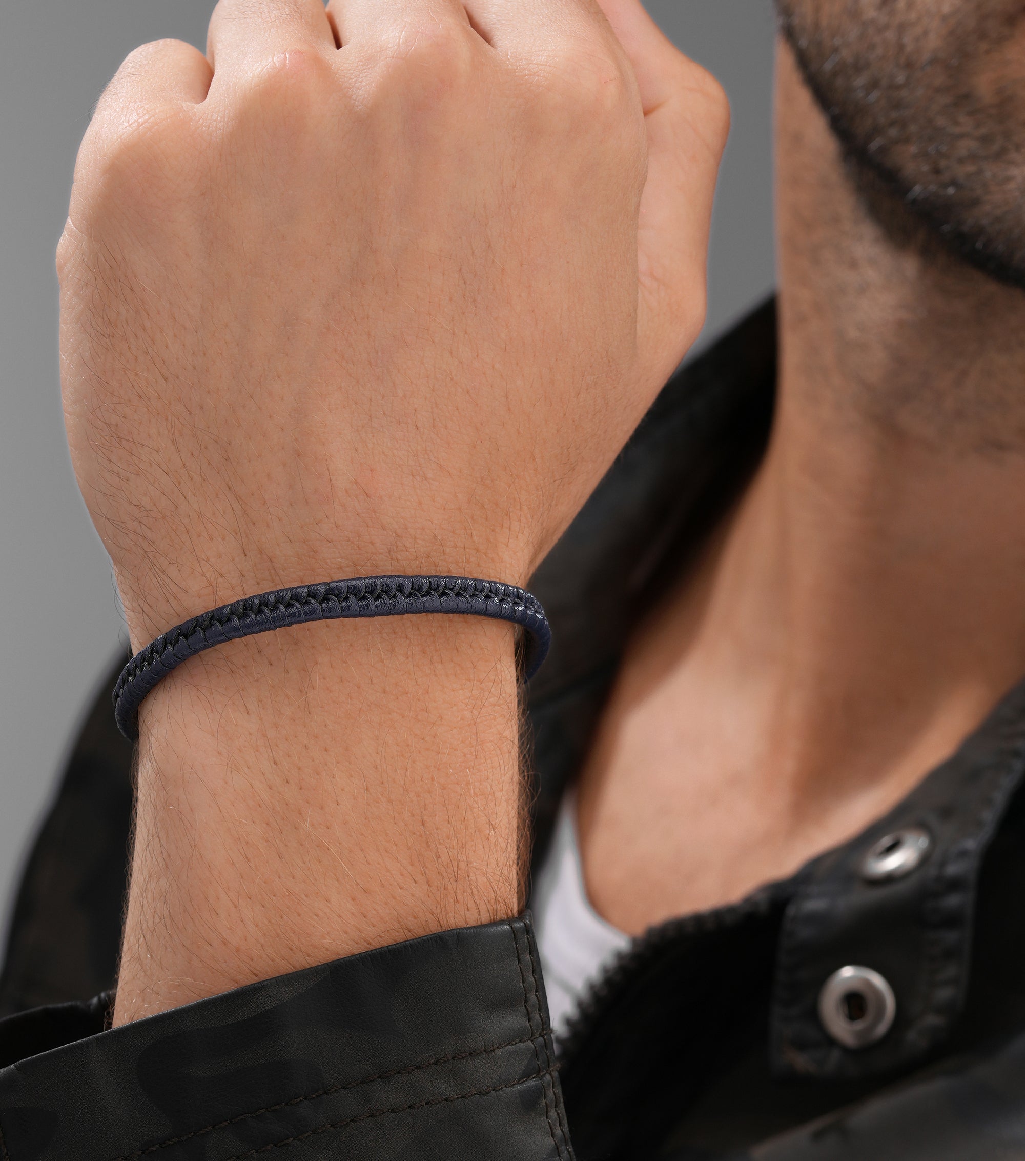 A dark blue braided leather bracelet. It features a continuous woven pattern around its circumference.