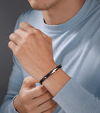Black leather bracelet with a silver-toned lightning bolt design in the center, flanked by small black studs.