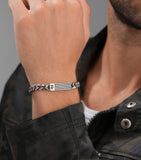 Silver-toned curb chain bracelet with a rectangular plaque featuring an initial "P" and a woven texture.