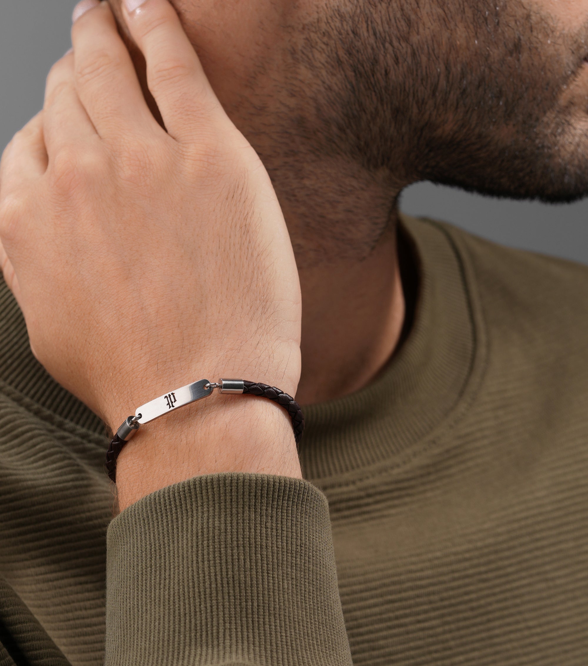 Brown braided leather bracelet with a silver-toned ID bar engraved with 'dt' in a gothic font.