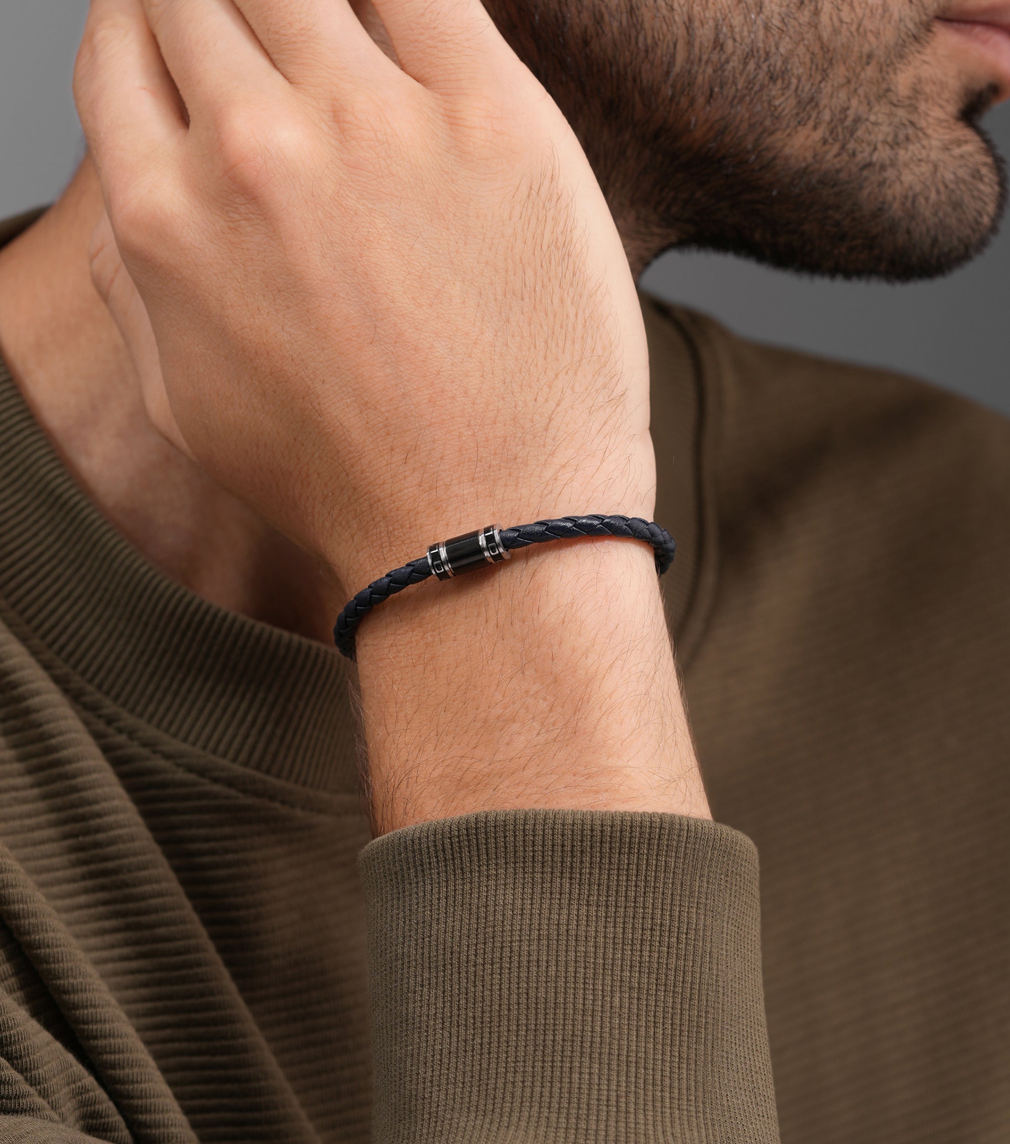 Slim blue braided leather bracelet featuring a black cylindrical clasp with two silver-toned rings.