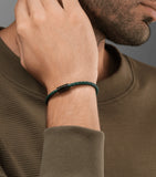 Slim green braided leather bracelet with a black cylindrical clasp.
