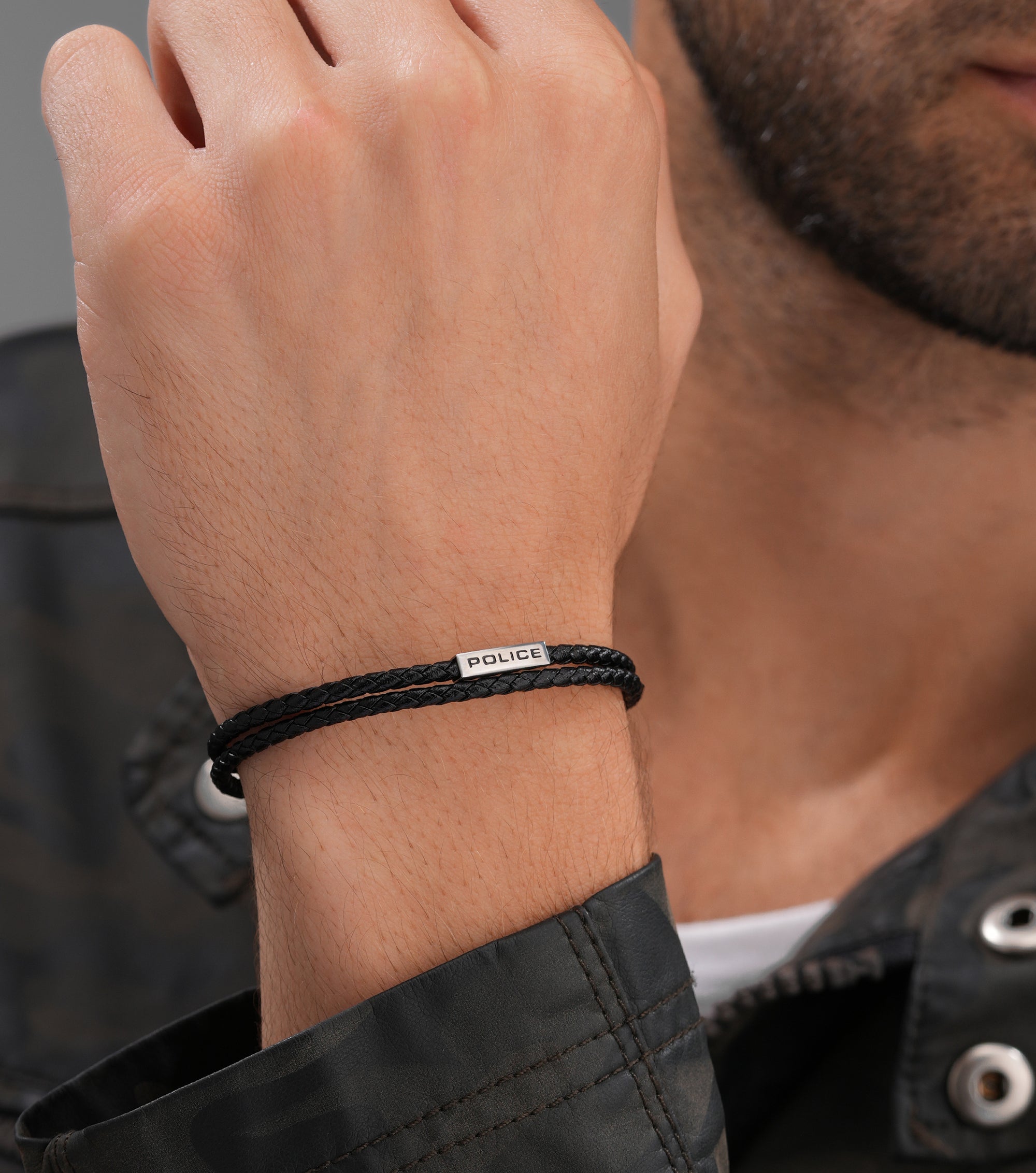 Black double-wrap braided leather bracelet with a silver-toned bar engraved 'POLICE'.