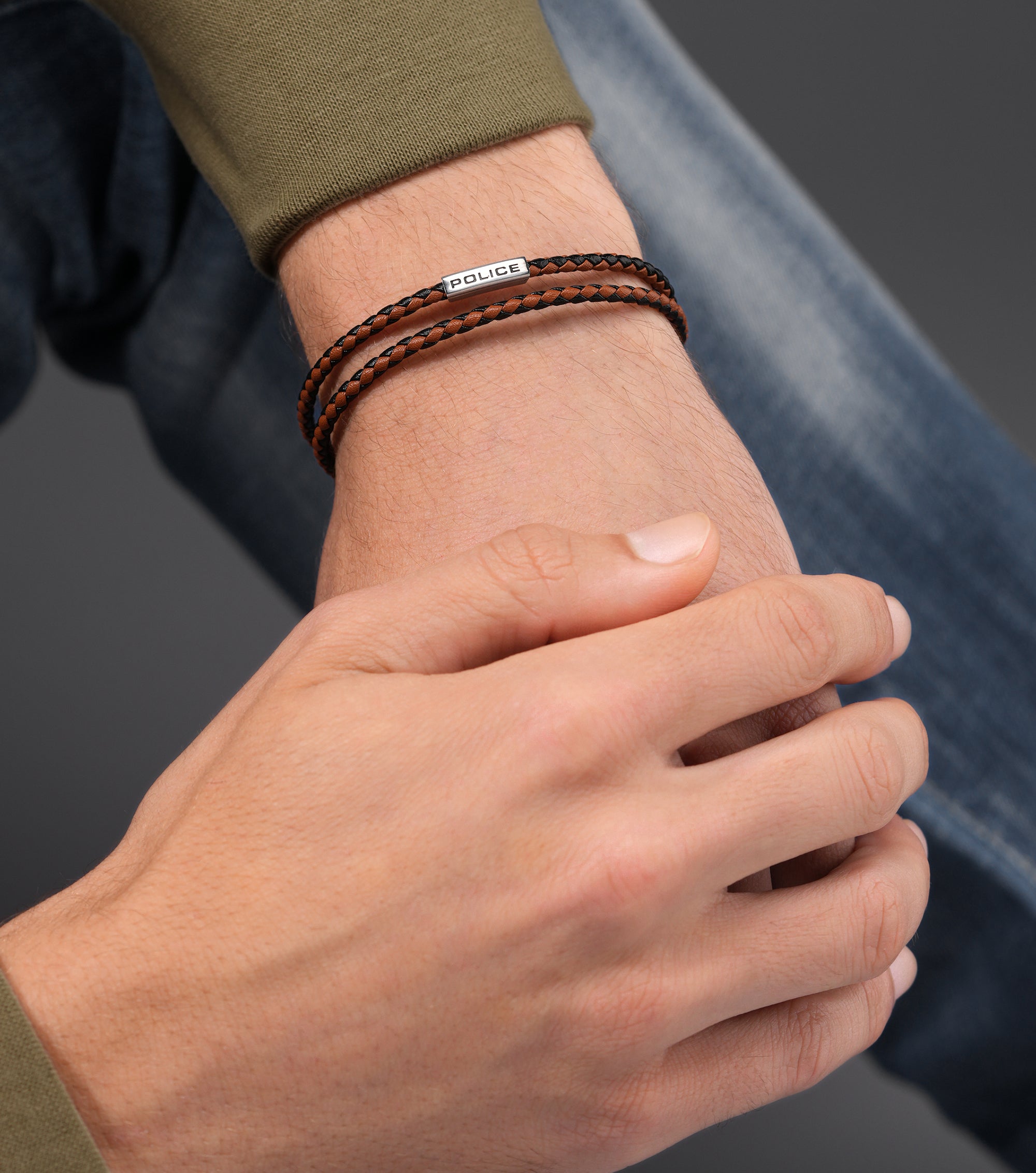 Double-wrap braided leather bracelet in brown and black with a silver-toned rectangular bar engraved with 'POLICE'.