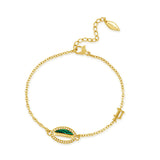 Gold-toned chain bracelet with an oval charm featuring green malachite and white mother-of-pearl inlay, surrounded by clear s