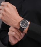 Silver-toned stainless steel watch with a black textured dial, silver-toned hands, two sub-dials, and a black leather strap.
