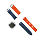 Silver-toned watch with gunmetal dial, orange accents. Dark blue leather and orange silicone straps with silver-toned buckles