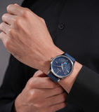 Round silver-toned watch with a blue textured dial, silver-toned markers, a sub-dial at 6, and a blue leather strap.