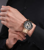 Round gold-toned watch with a black textured dial, three sub-dials, gold-toned hands, and a gold-toned link bracelet.