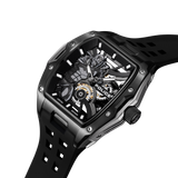 Black rectangular watch with a 3D Batman figure on a skeletonized dial, showing gold-toned gears. Black silicon strap with cu