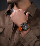 Gunmetal-black watch with a black dial, white markings, red accents, and an orange ribbed silicon strap.