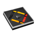 Black TR90 watch with skeleton dial and four silicon straps in black, red, and two shades of yellow, presented in a box.