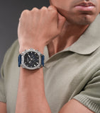 Silver-toned stainless steel watch with an angular case, black and blue chronograph dial, and a blue silicone strap.