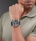 Silver-toned stainless steel watch with a black chronograph dial, silver-toned hour markers, and a black silicon strap.
