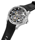 Silver-toned automatic watch with a skeleton dial revealing gears, black outer ring, numbered bezel, and a black textured sil