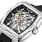 Silver-toned rectangular steel watch with a black silicone strap and a skeleton black dial revealing silver and gold-toned ge