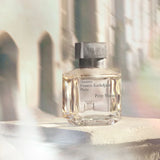 Clear glass perfume bottle with a silver-toned rectangular cap. Text "Maison Francis Kurkdjian Paris Petit Matin" on the fron