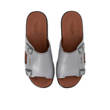 Overhead view of a pair of PRESTIGE grey leather slide sandals with tan footbeds and silver buckles.