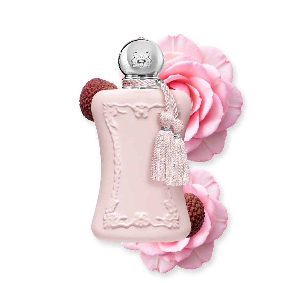 A 75ml bottle of Parfums de Marly Delina perfume in pastel pink, artfully surrounded by blossoming pink roses and fresh lychee fruits.